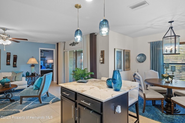 kitchen featuring light tile patterned floors, visible vents, open floor plan, a breakfast bar, and pendant lighting