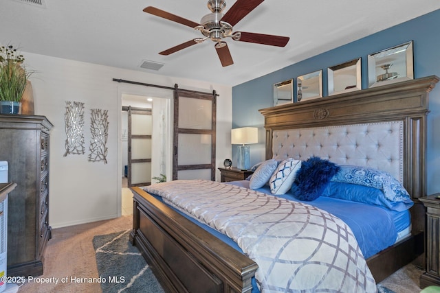 bedroom with a barn door, carpet, visible vents, and baseboards