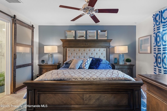 bedroom with a barn door, ceiling fan, and light colored carpet