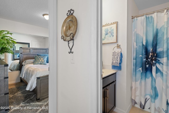 ensuite bathroom featuring curtained shower, ensuite bath, a textured ceiling, and vanity