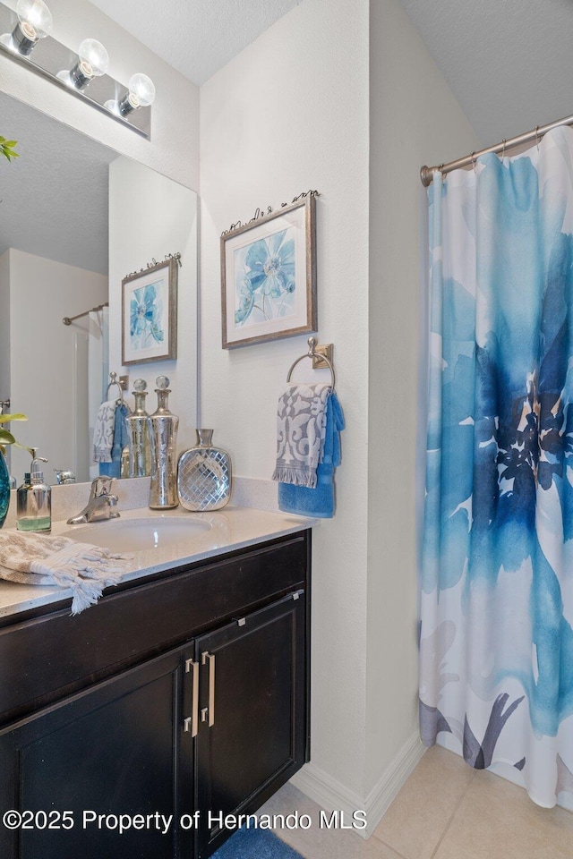 full bathroom featuring baseboards, vanity, a textured ceiling, and tile patterned floors