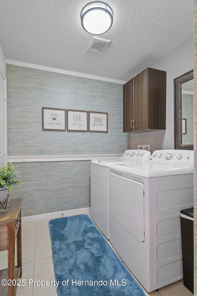 washroom with light tile patterned floors, separate washer and dryer, a textured ceiling, and cabinet space