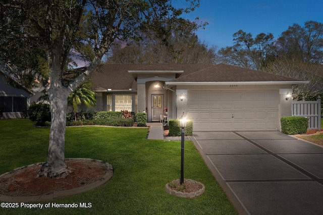 ranch-style home with a shingled roof, a front lawn, stucco siding, driveway, and an attached garage