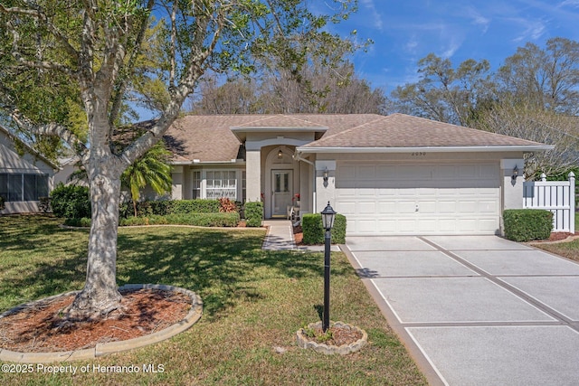 ranch-style home featuring a front lawn, fence, stucco siding, driveway, and an attached garage