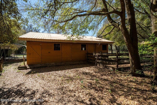 rear view of property featuring an outbuilding, metal roof, dirt driveway, a carport, and an exterior structure