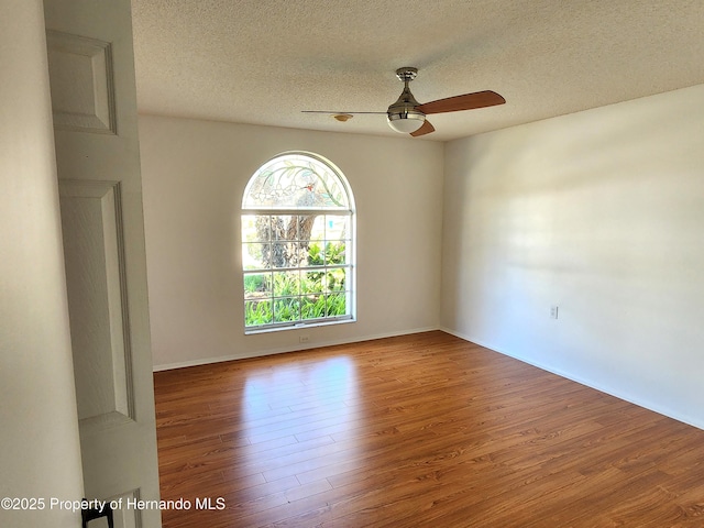 7106 Green Abbey Way, Spring Hill, FL 34606 - empty room with wood finished floors, a ceiling fan, a textured ceiling, and baseboards