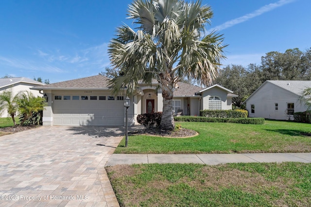 view of front of house featuring an attached garage, a front yard, decorative driveway, and stucco siding