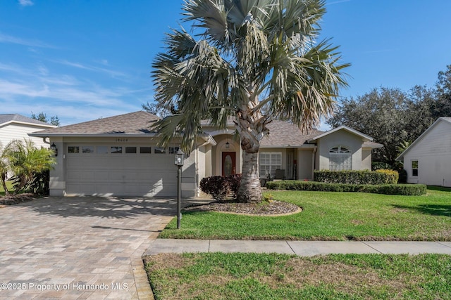 view of front facade featuring a garage, stucco siding, decorative driveway, and a front yard