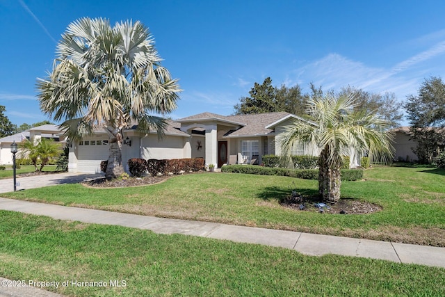 view of front of home featuring an attached garage, driveway, a front lawn, and stucco siding