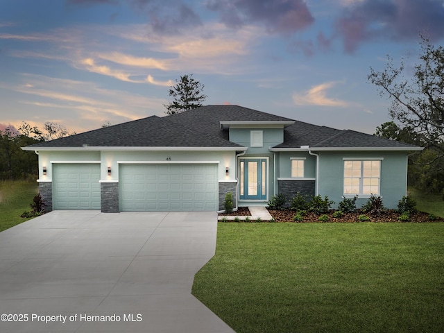 prairie-style home with an attached garage, driveway, stone siding, stucco siding, and a front lawn