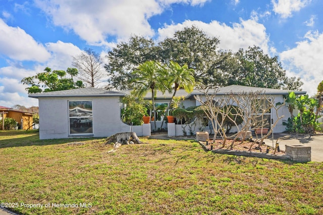 rear view of property featuring a yard and stucco siding