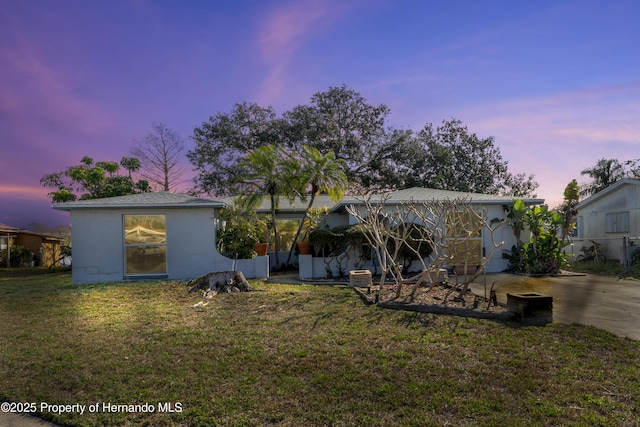 back of property at dusk featuring a yard