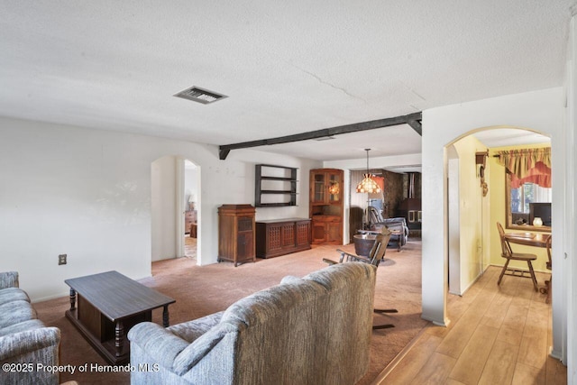 living area featuring visible vents, arched walkways, and a textured ceiling