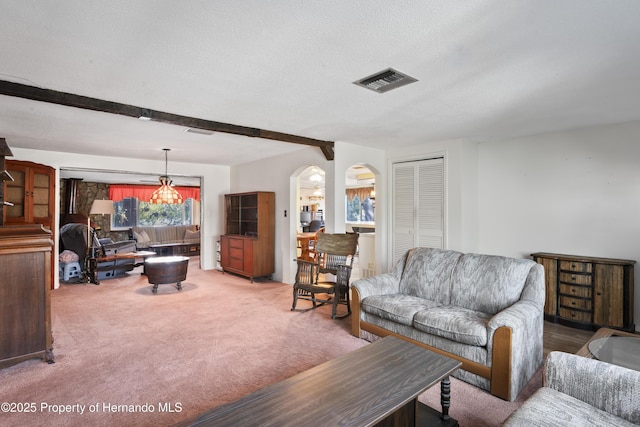 living area with arched walkways, a textured ceiling, light colored carpet, visible vents, and beamed ceiling