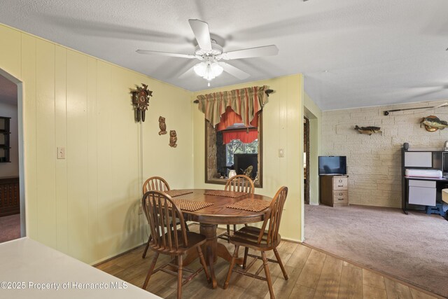 dining space with ceiling fan, a textured ceiling, and wood finished floors