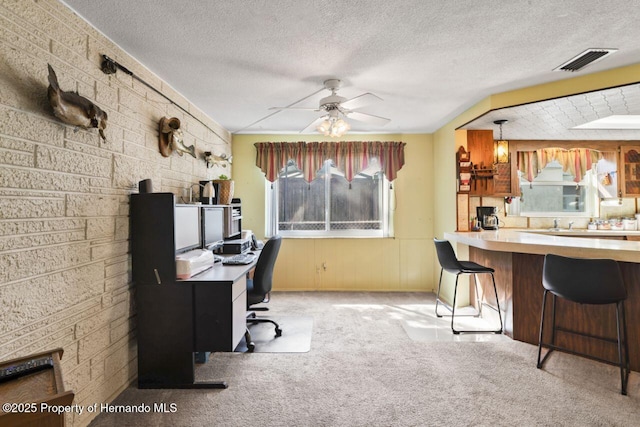 carpeted office space featuring a textured ceiling, visible vents, and a ceiling fan