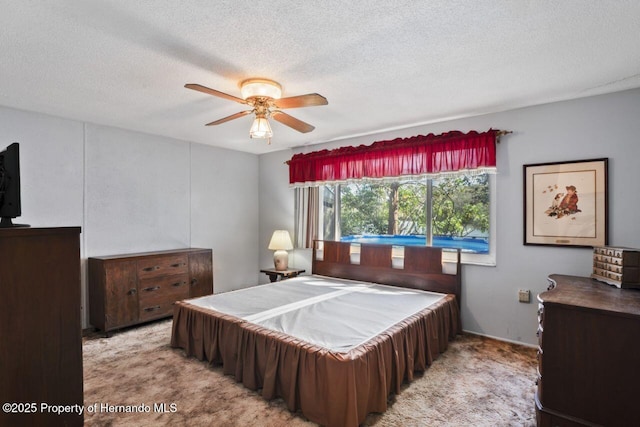 bedroom featuring carpet floors, ceiling fan, and a textured ceiling