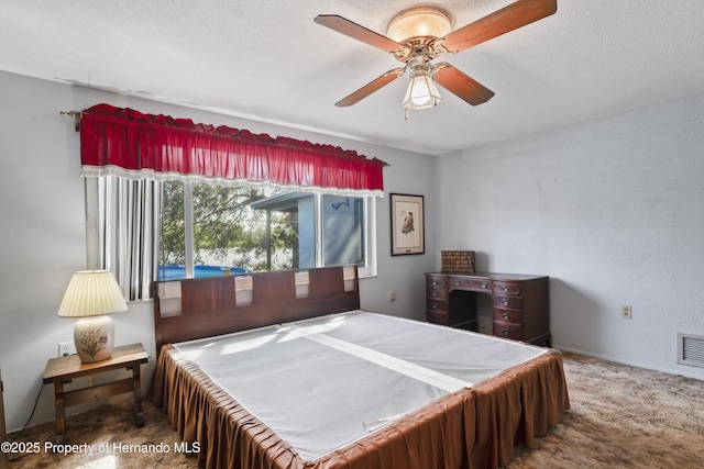 bedroom featuring a textured ceiling, carpet floors, ceiling fan, and visible vents