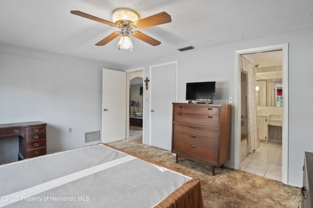 bedroom featuring carpet floors, visible vents, arched walkways, and a textured ceiling