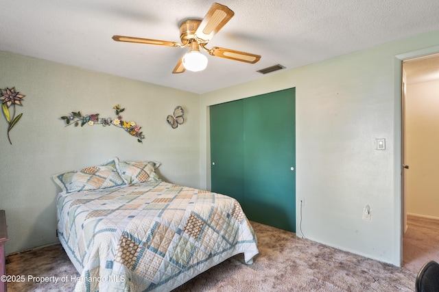 bedroom with a textured ceiling, ceiling fan, visible vents, a closet, and carpet