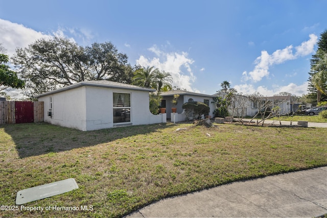 ranch-style home featuring a front yard, fence, and stucco siding