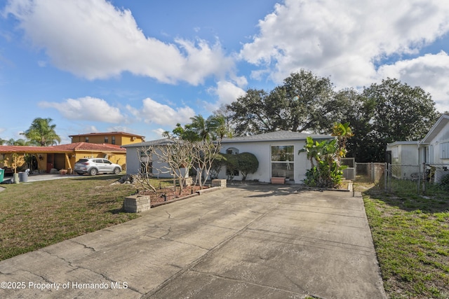 view of front of home featuring a front yard, concrete driveway, a gate, and stucco siding