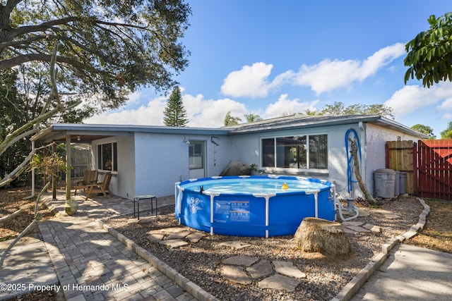 back of house with a fenced in pool, a patio area, fence, and stucco siding