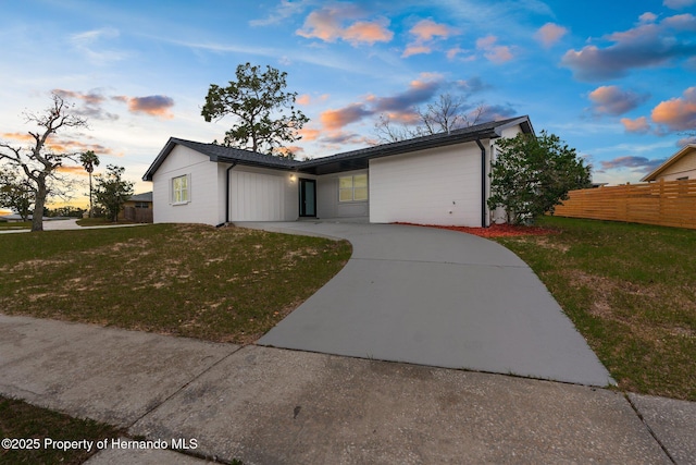 view of front of home featuring a garage, a yard, fence, and driveway