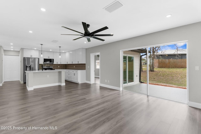 unfurnished living room with ceiling fan, dark wood-type flooring, visible vents, and recessed lighting