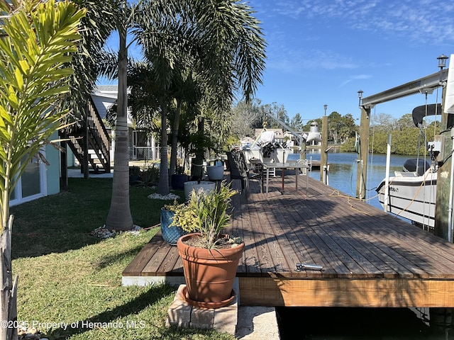 view of dock with a water view, a yard, and boat lift