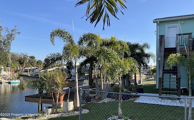 exterior space with stairs, a water view, and fence