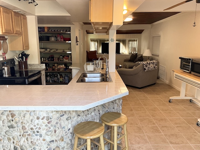 kitchen with tile countertops, light tile patterned floors, open floor plan, a sink, and black / electric stove