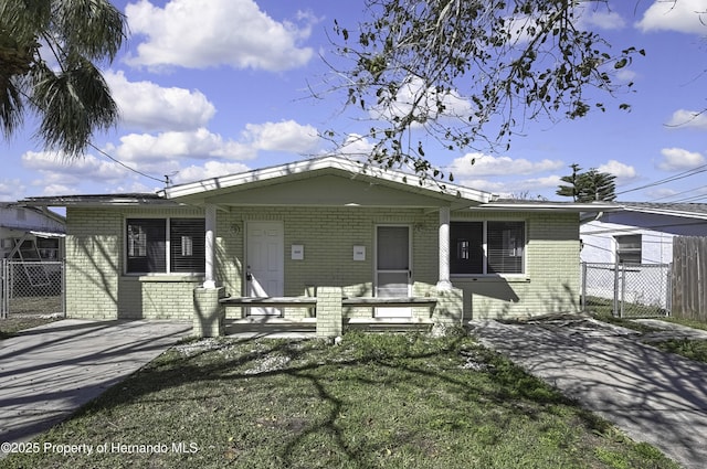 view of front of house with a front yard, concrete driveway, brick siding, and fence