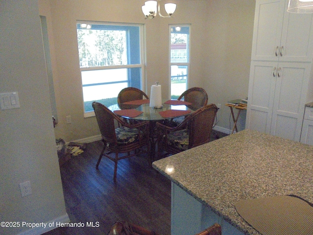 dining area with dark wood-type flooring, an inviting chandelier, and baseboards