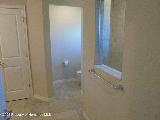 bathroom featuring baseboards and toilet