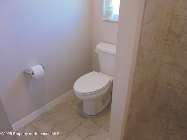 bathroom with tiled shower, tile patterned flooring, toilet, and baseboards