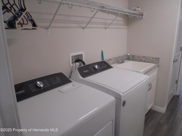 laundry room with dark wood-type flooring, independent washer and dryer, a sink, and cabinet space