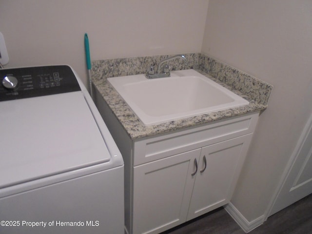 laundry room with dark wood finished floors, a sink, washer / dryer, and baseboards