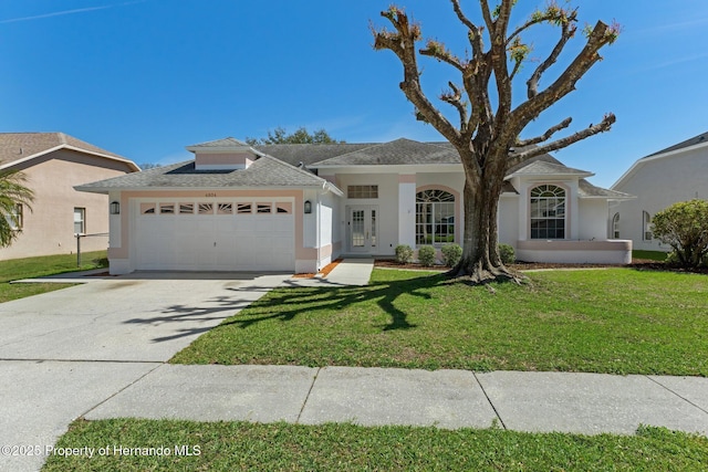 view of front of property featuring an attached garage, concrete driveway, french doors, stucco siding, and a front yard