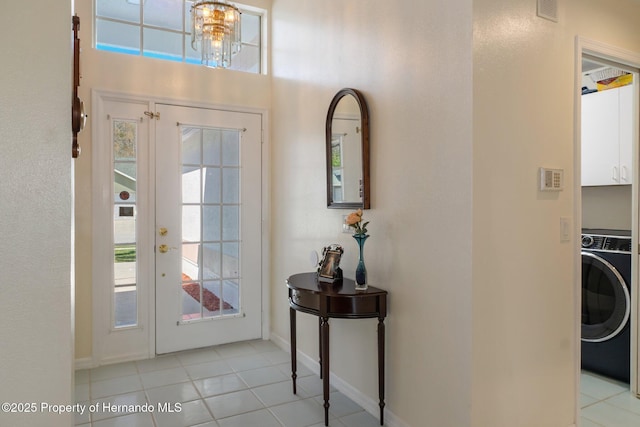 foyer featuring washer / dryer, visible vents, baseboards, an inviting chandelier, and light tile patterned flooring