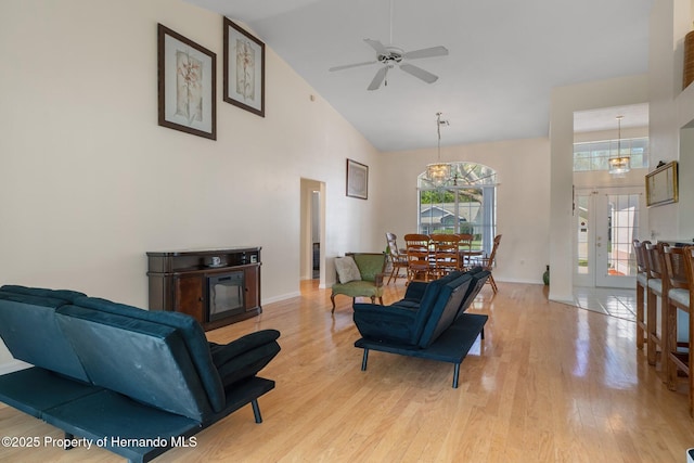 living area featuring baseboards, high vaulted ceiling, and light wood-style floors