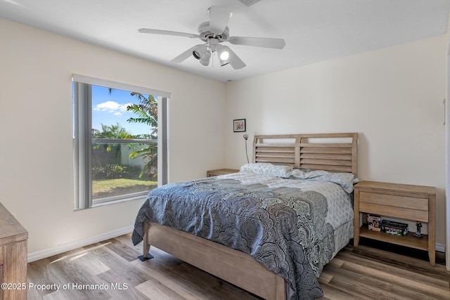 bedroom featuring ceiling fan, baseboards, and wood finished floors