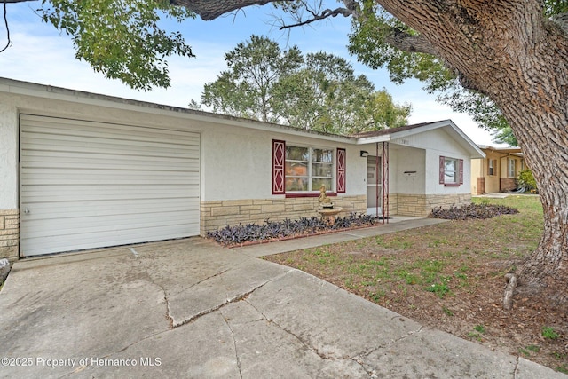 single story home with driveway, stone siding, a garage, and stucco siding