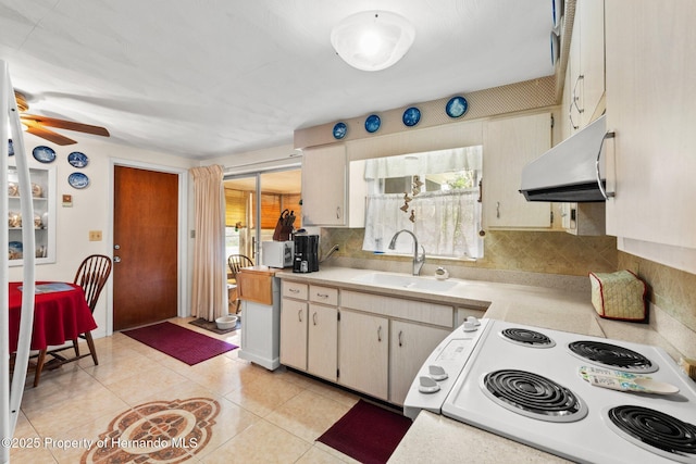 kitchen with a sink, light countertops, ventilation hood, electric range oven, and tasteful backsplash