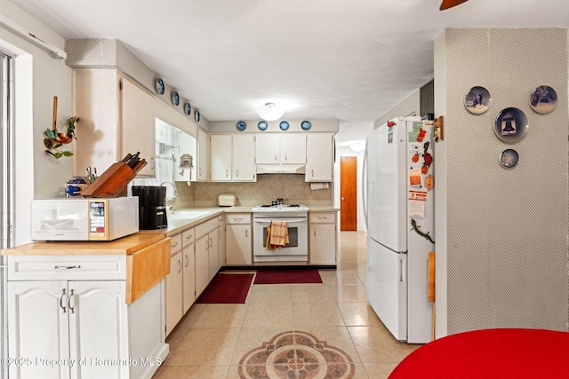 kitchen featuring white appliances, decorative backsplash, under cabinet range hood, a sink, and light tile patterned flooring