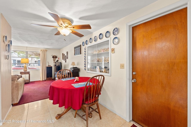 tiled dining space featuring ceiling fan and baseboards