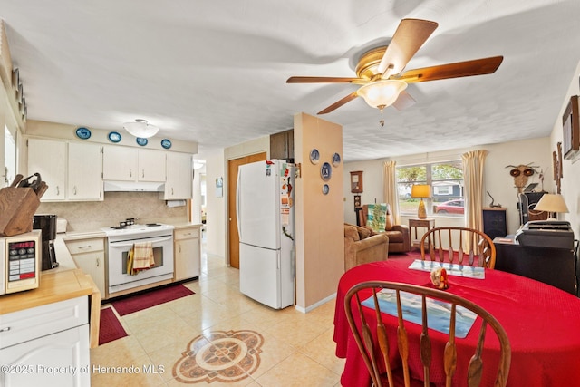 kitchen with light tile patterned floors, decorative backsplash, white cabinets, white appliances, and under cabinet range hood