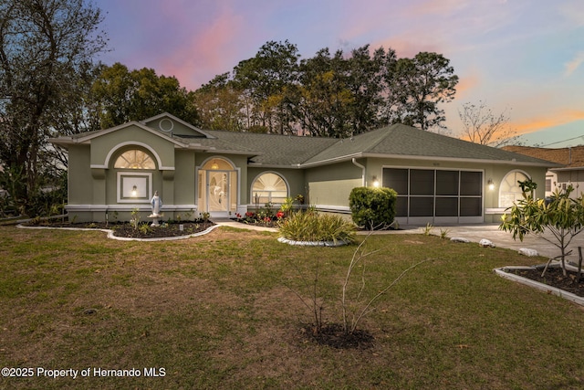 ranch-style house featuring concrete driveway, a lawn, an attached garage, and stucco siding