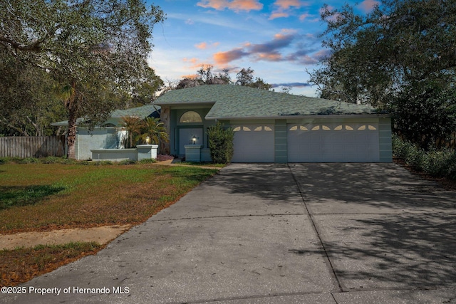 ranch-style home with a garage, driveway, and fence