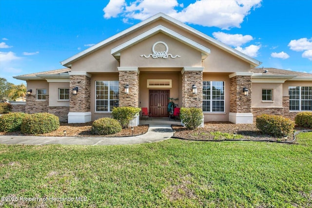 view of front of property featuring stone siding, a front yard, and stucco siding